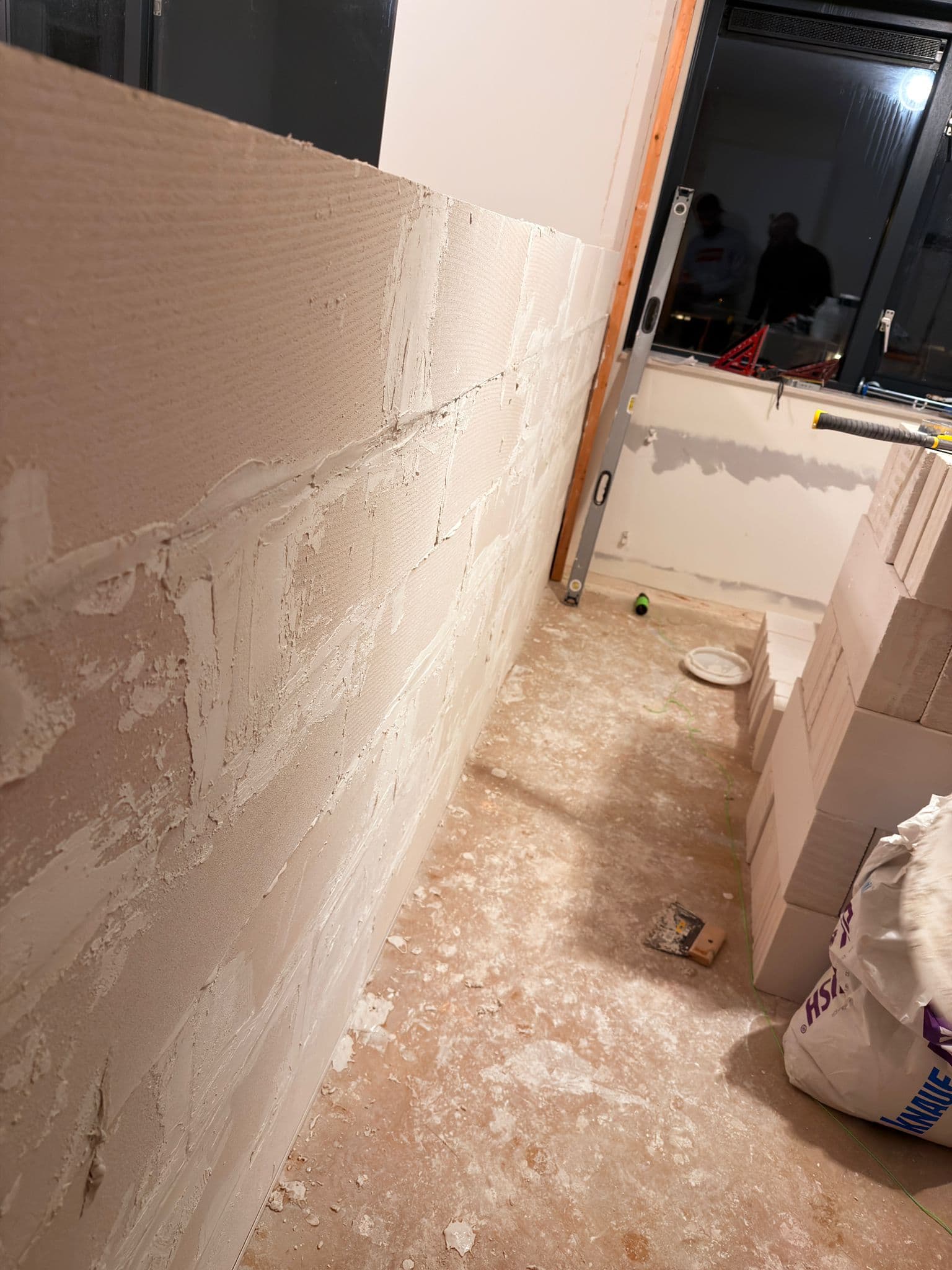 A partially built wall of light-colored aerated concrete blocks with visible white mortar joints.
